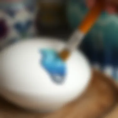Close-up of a ceramic piece being painted with a brush